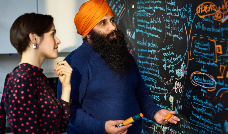 Three people collaborating together in an office while looking at some printed documents.